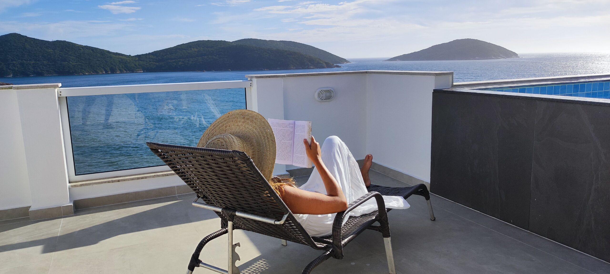 Elegant seaside lounge scene bathed in warm sunlight, evoking the relaxed sophistication of continental afternoons by the sea.