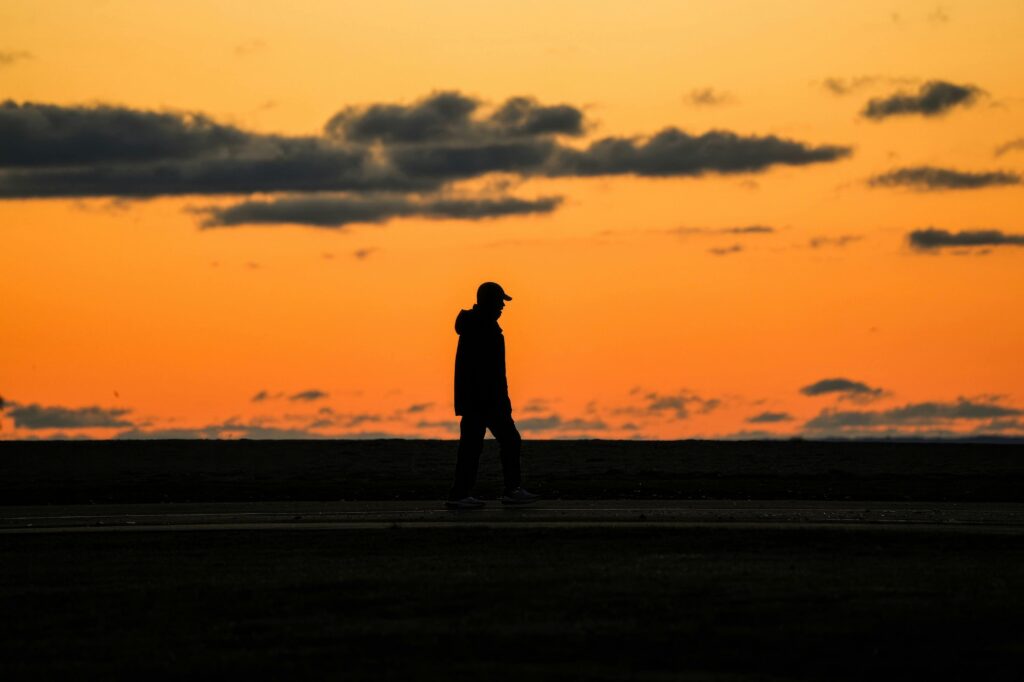 Person walking alone toward the horizon at sunset