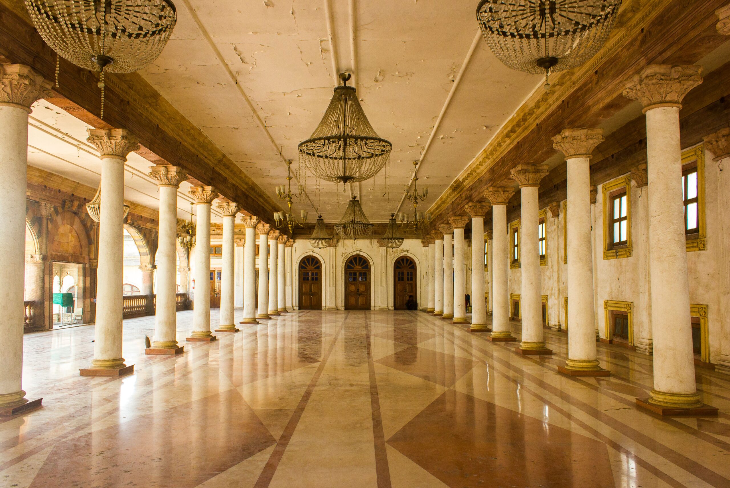 A magnificent historic ballroom with marble floors, grand columns, and crystal chandeliers, reflecting the timeless elegance of orchestral string music.