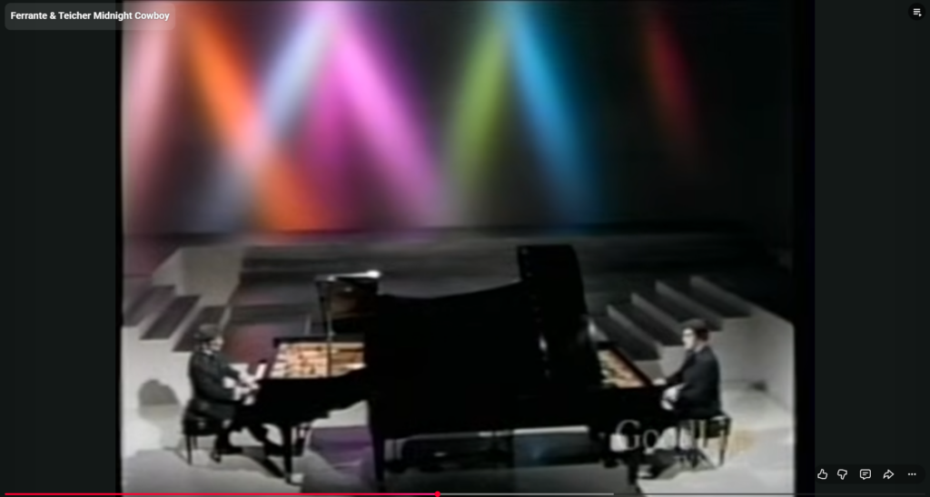 Ferrante & Teicher performing together at two grand pianos with full orchestral accompaniment during a live concert.