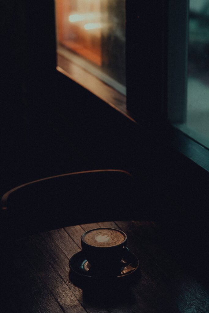 A cup of coffee on a table at dusk, illustrating how late-day caffeine can affect sleep later at night.