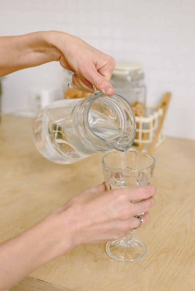 A person pouring a glass of water in the morning before drinking coffee.