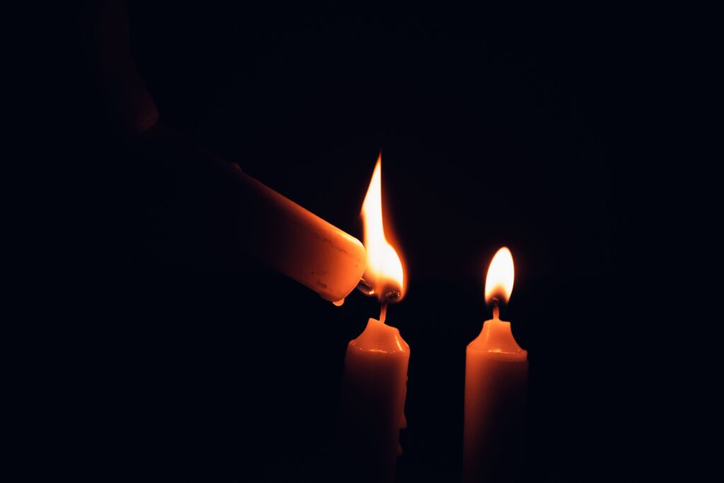 A candle flame sustained by melting wax, symbolizing how craving keeps the cycle of rebirth going