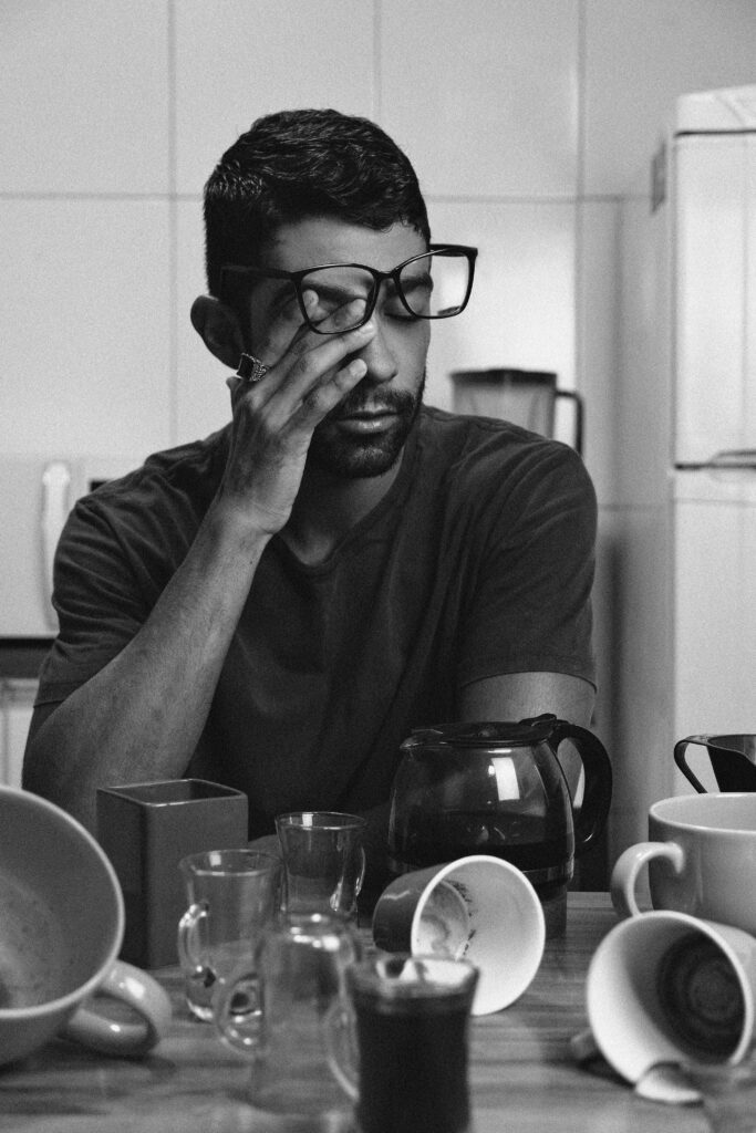 A tired person sitting beside an unfinished cup of coffee